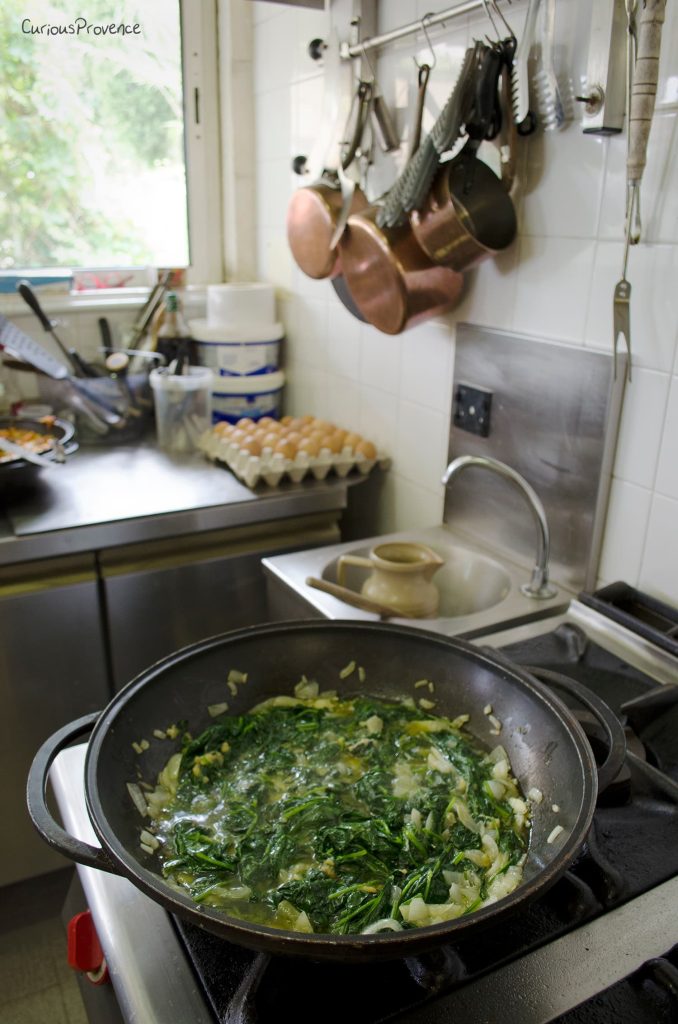 Épinards bio du jardin sautés aux oignons en cuisine professionnelle au Mas des Figues, recette garden-to-table à Saint-Rémy-de-Provence